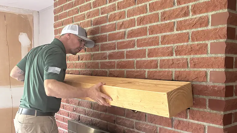 Carpentry handyman in Fremont mounting a custom wooden mantel on a brick fireplace.