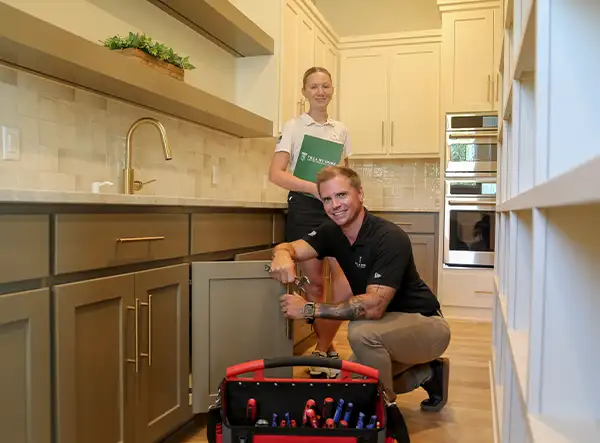 Contact Villa My Home handyman in Omaha repairing kitchen cabinets with tools while a team member provides support. Handyman Cost Omaha