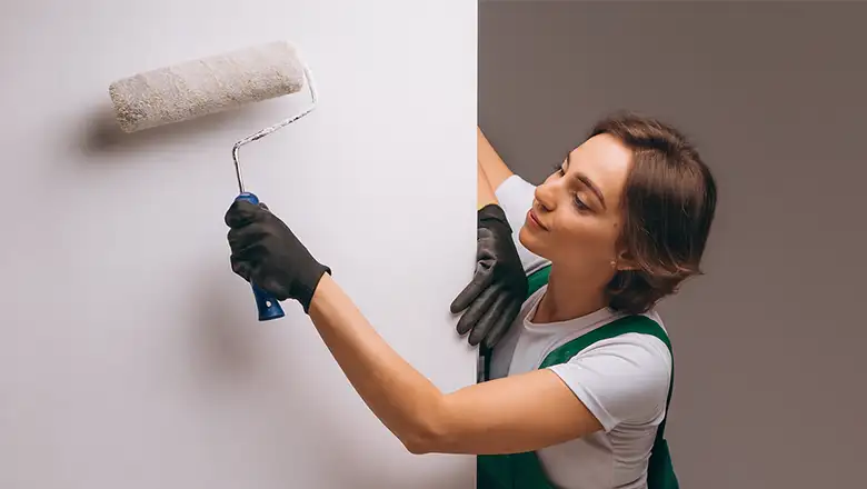 Painting handyman in Omaha applying fresh interior wall paint with a roller preparing for rental unit inspection